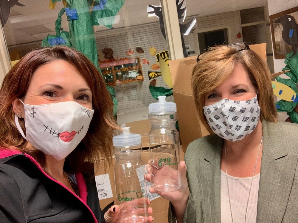 Two individuals wearing masks showing off water bottles