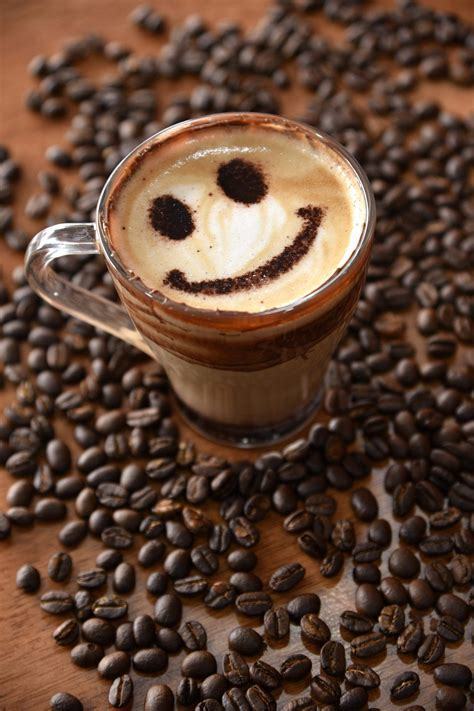 Coffee cup  with smiley face in the coffee cream surrounded by coffee beans