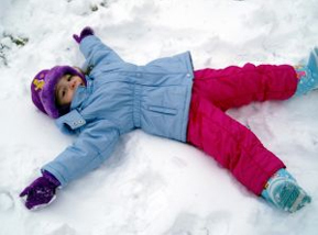 Child making a snow angel in winter gear