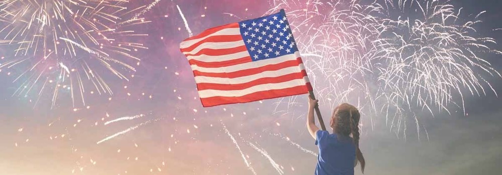 Child waving US flag with fireworks