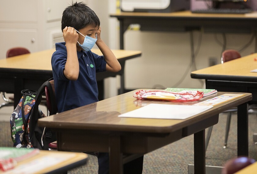 Student at desk taking off mask
